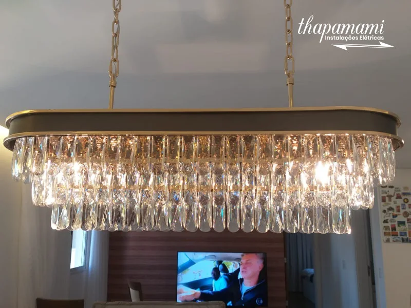 Luminária linear de cristal instalada sobre mesa de jantar