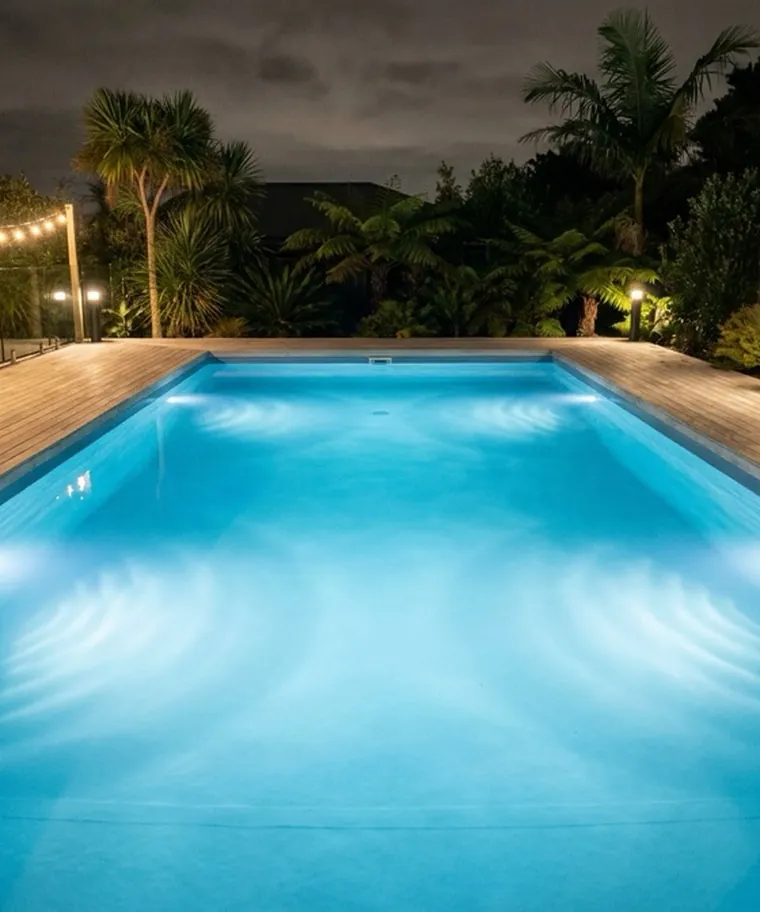 Piscina residencial com iluminação LED acesa dentro da água, à noite